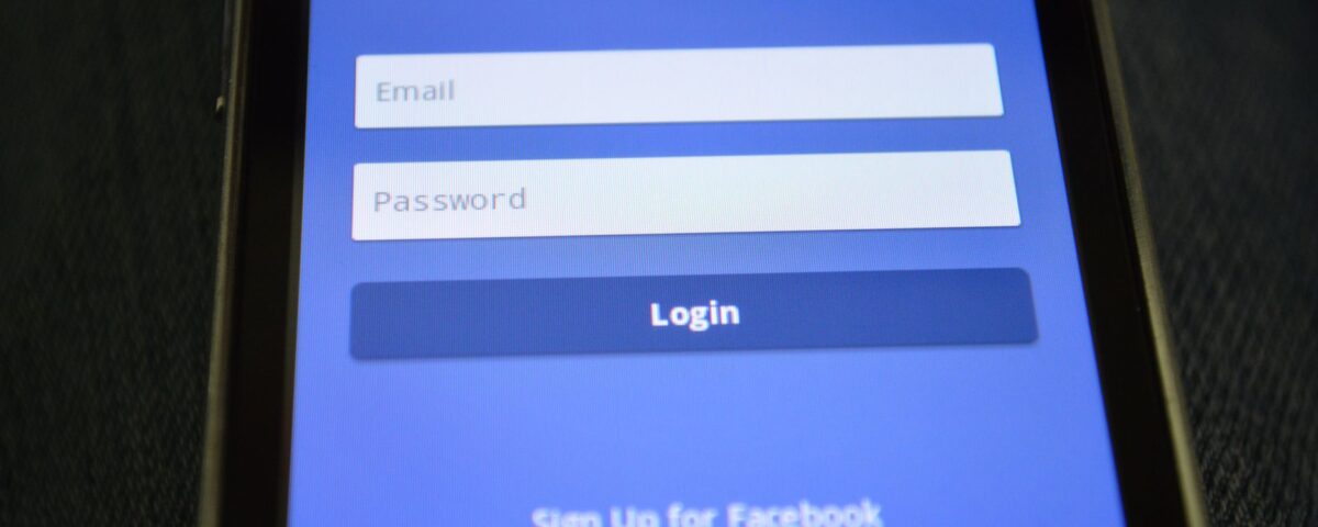 Hardware security key held near laptop showing two-factor authentication login screen