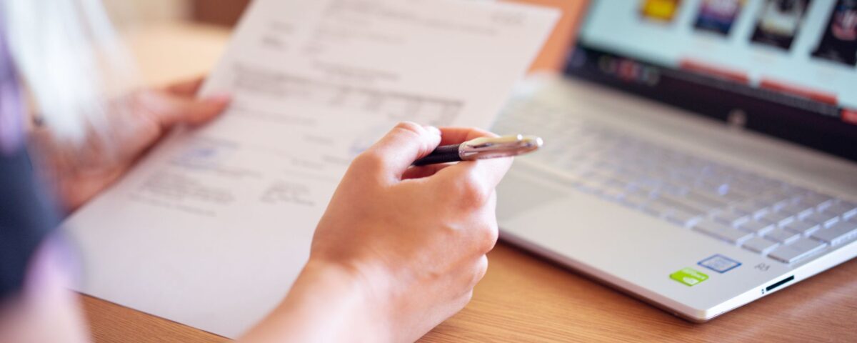 Professional performing a personal security audit on a laptop with checklist