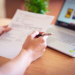 Professional performing a personal security audit on a laptop with checklist