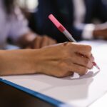 Robotic arm writing on legal document at office desk with books