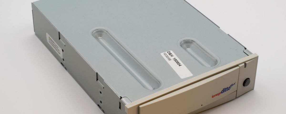 IT technician loading backup tape cartridges in an enterprise server room during disaster recovery