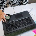 Employee using smartphone MFA code to log into corporate laptop