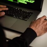 Researcher analyzing neural network code on laptop screen for AI security vulnerabilities