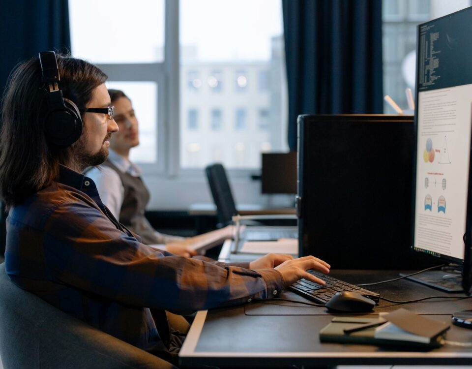 Security analyst reviewing AI pipeline code logs on dual monitors