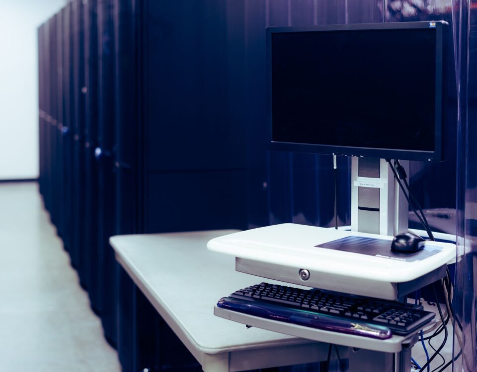 Dense cable trays running between illuminated server racks in a data center