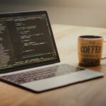 Developer laptop with code editor open and USB drives connected at desk
