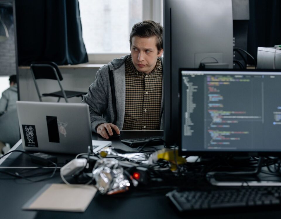 Developer reviewing GraphQL API query code on terminal screens at desk